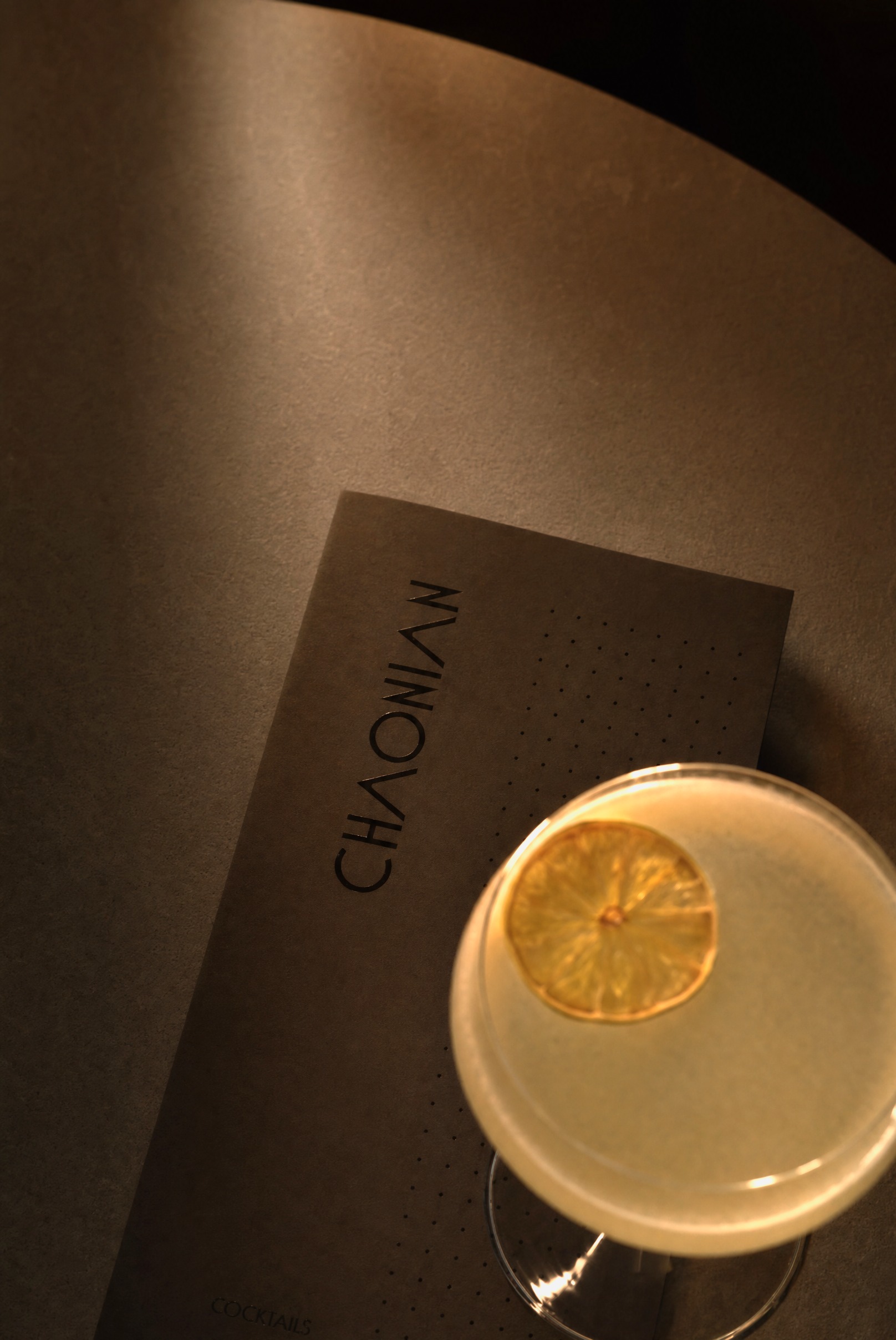 Lobby Bar — a citrus cocktail beside the Chaonian menu