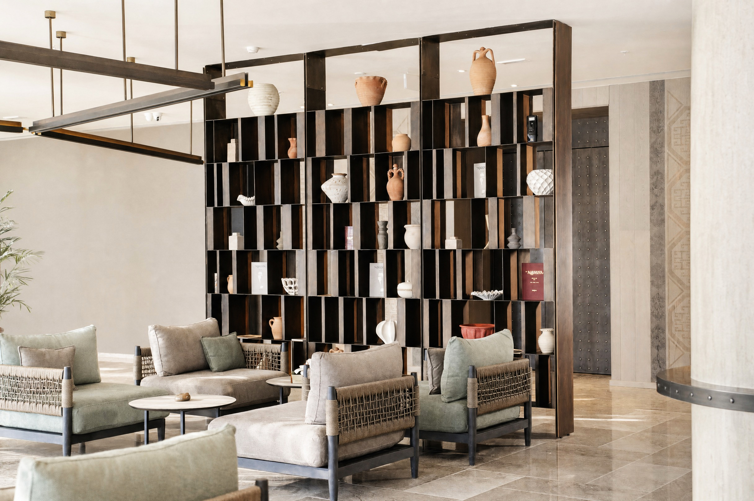 Lobby lounge — woven armchairs before a shelf of Albanian pottery