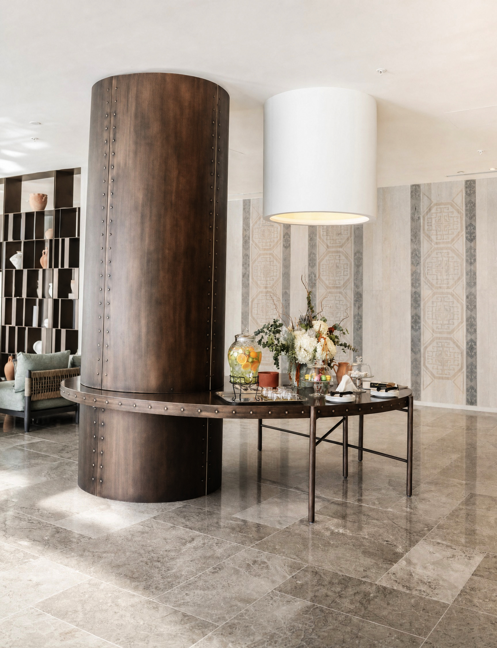 The arrival welcome table beside a copper-clad column, set with citrus-infused water and seasonal blooms